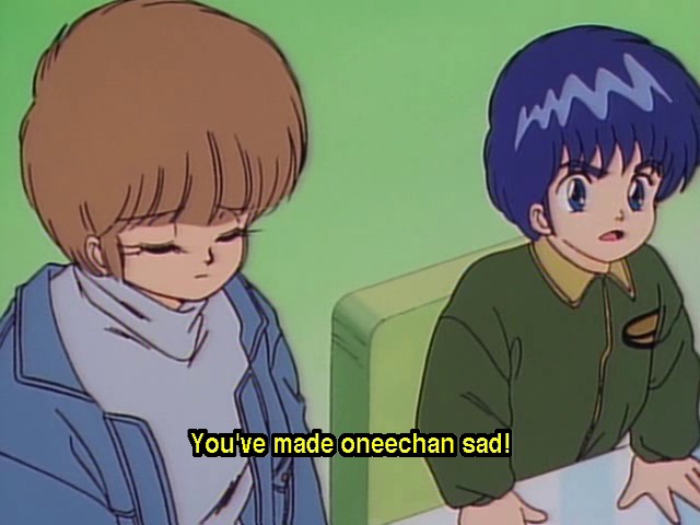 Stopklatka przedstawiająca postacie z serialu Kimagure Orange Road: po lewej, zasmucona Hikaru Hiyama siedzi z zamkniętymi oczami, po prawej wzburzony Kazuya upomina swojego starszego kuzyna słowami "You've made oneechan sad!" widocznymi w formie żółtych napisów na ekranie.